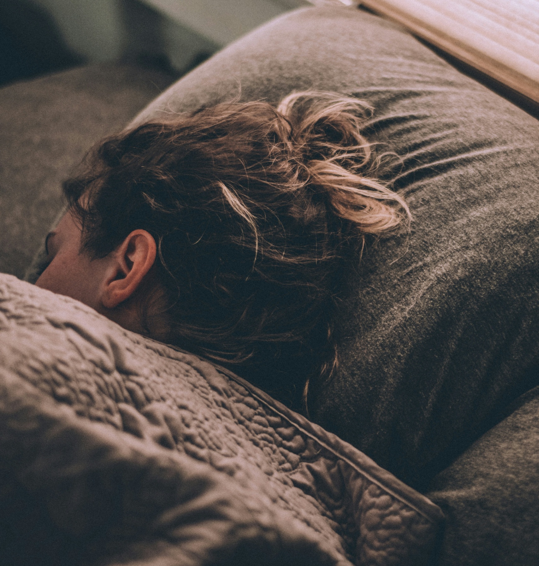 A person resting peacefully on a soft couch in warm evening light